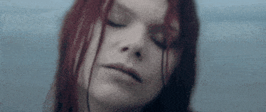 a close up of a woman 's face with red hair and her eyes closed