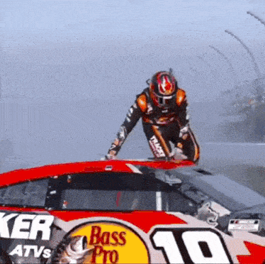 a man is standing on top of a race car sponsored by bass pro