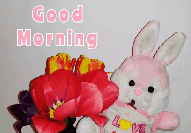 a pink and white stuffed bunny holding flowers with the words good morning written above it