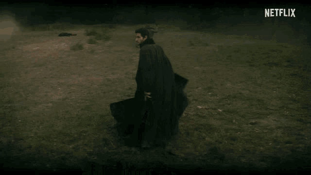 a man in a cape is walking in a field with netflix written on the bottom
