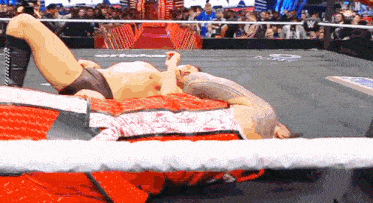 two wrestlers are wrestling in a ring with a crowd watching .