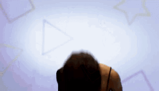 a woman is standing in front of a wall with triangles and stars on it