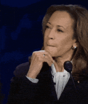 a woman is sitting in front of a microphone with her hand on her chin and a ring on her finger .