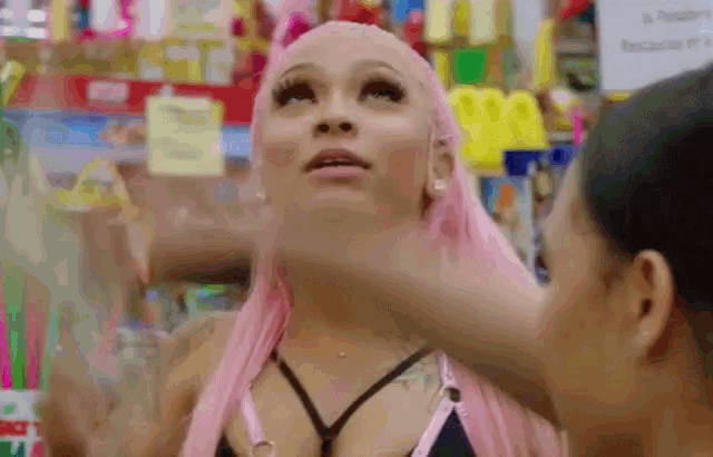 a woman with pink hair is being touched by another woman in a store