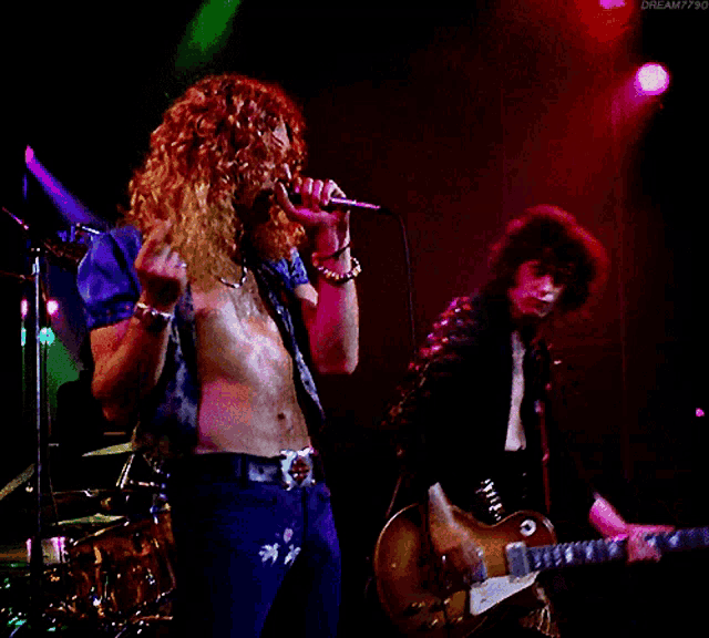 a man singing into a microphone and another man playing a guitar