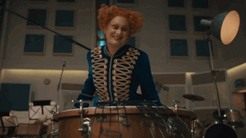 a woman with red hair playing a drum set