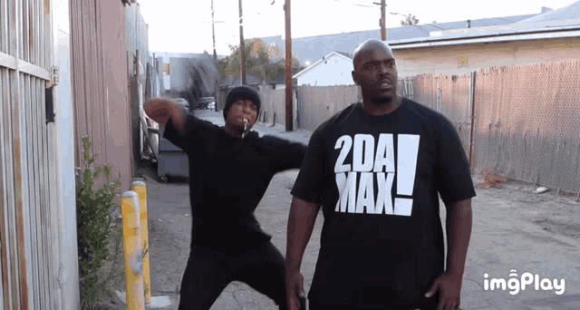 a man wearing a 2da max t-shirt is standing next to another man