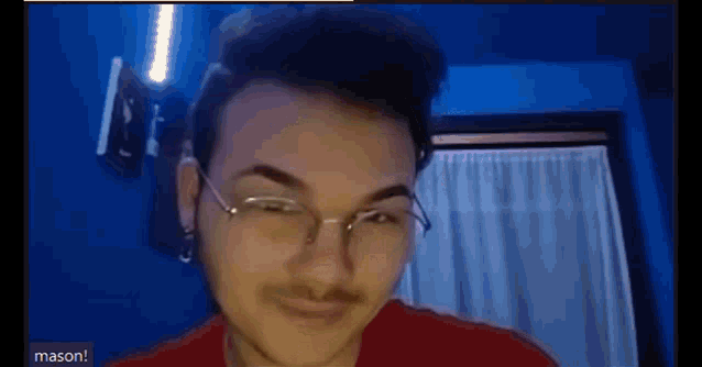 a young man wearing glasses and a red shirt is making a funny face .