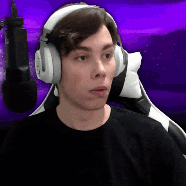a man wearing headphones and a black shirt is sitting in front of a purple background