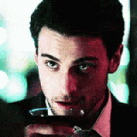 a man in a suit and tie is holding a glass in his hand .