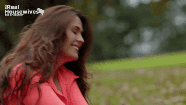a woman in a red shirt is smiling in front of a real housewives logo
