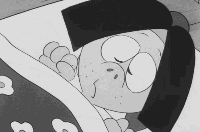 a cartoon character is sleeping in a bed with a blanket with flowers on it