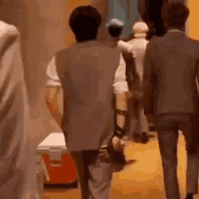 a group of people are walking down a hallway in a room .
