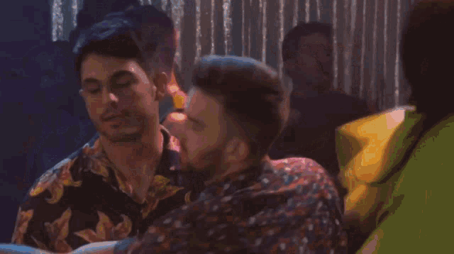 two men are standing next to each other in a crowd at a party
