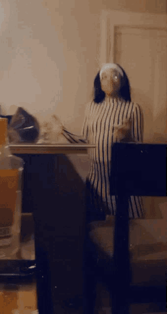 a woman in a striped shirt sits in front of a laptop