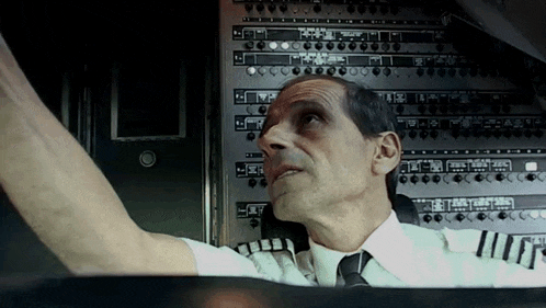 a man in a pilot 's uniform is looking up at the controls