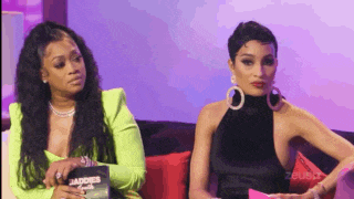 two women are sitting next to each other on a couch and one of them is holding a sign that says cuadros