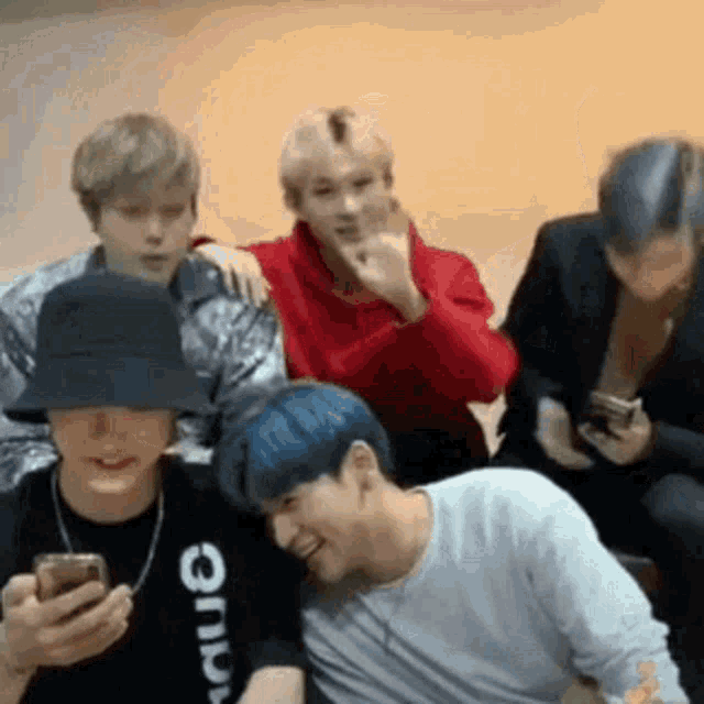 a group of young men are sitting next to each other and looking at their phones .