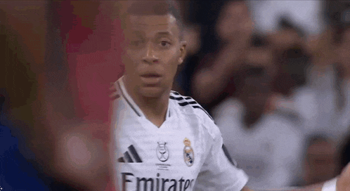 a soccer player wearing a white emirates jersey is looking at the camera .