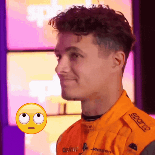 a close up of a man wearing an orange jacket that says sparco