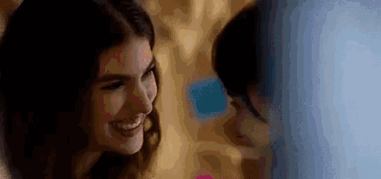 two women are smiling at each other and looking at each other in a room .