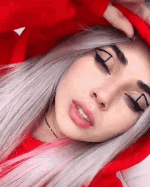 a girl with gray hair is wearing a red hoodie and a choker necklace .