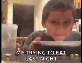 a young boy is sitting at a table with a plate of food and a cup of water .