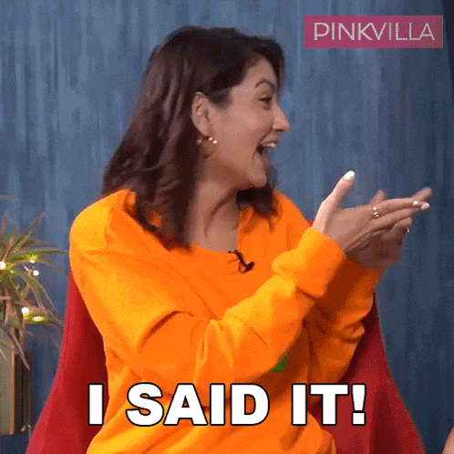a woman wearing an orange sweater is clapping and saying i said it