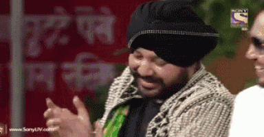 a man wearing a turban is laughing with another man in front of a sign that says sony
