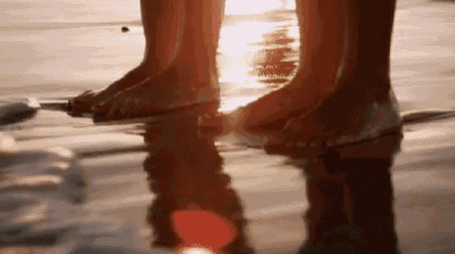 a couple 's feet are reflected in the water