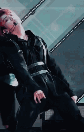 a man is laying on his back on a stage while wearing a microphone .