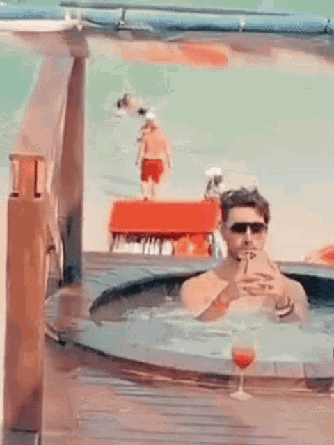 a man is sitting in a hot tub drinking wine