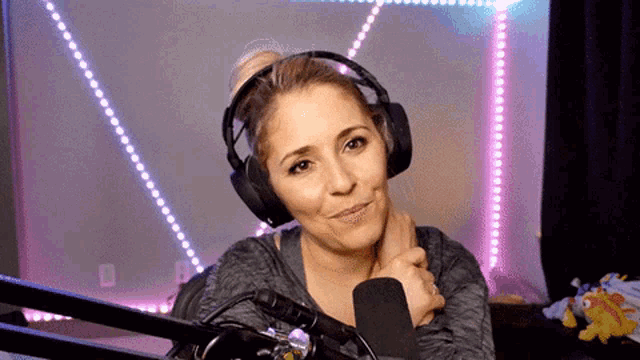 a woman wearing headphones and a microphone is smiling