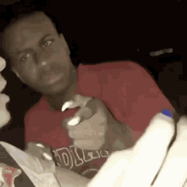 a man in a red shirt is holding a bottle of water and eating a bag of chips .