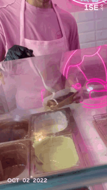 a man in a pink apron is pouring ice cream
