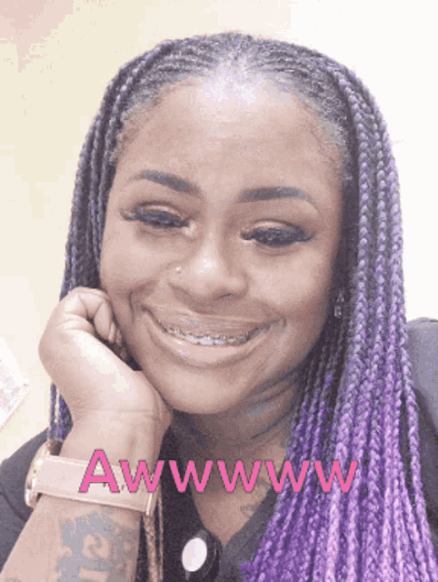 a woman with purple braids is smiling and says awwww in pink