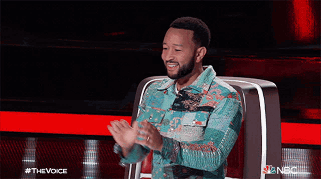 a man is sitting in front of a microphone and applauding on the voice show