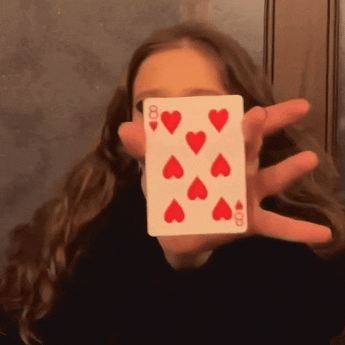 a girl is holding up a queen of hearts card