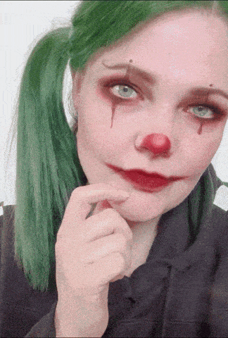 a woman with green hair is dressed as a clown with blood dripping from her nose