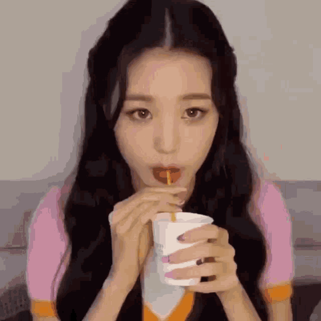 a woman is drinking a drink through a straw from a cup .