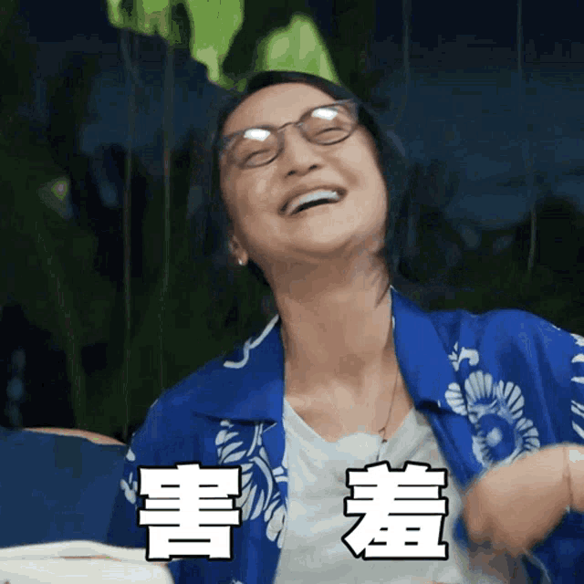 a woman wearing glasses and a blue shirt is laughing with chinese characters above her