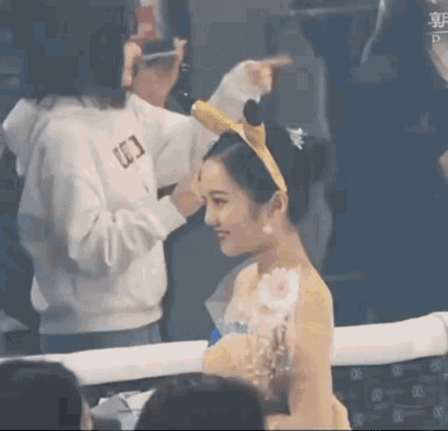 a woman is getting her hair done in a boxing ring while another woman watches .