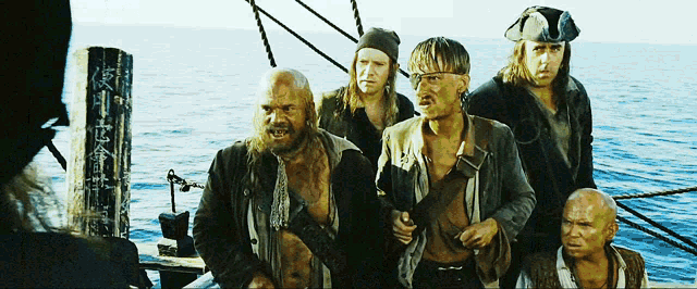 a group of men are standing on a boat in the ocean and one of them is wearing a pirate hat