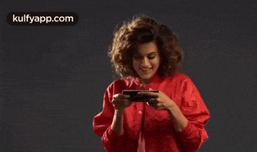 a woman in a red jacket is holding a cell phone in her hands .
