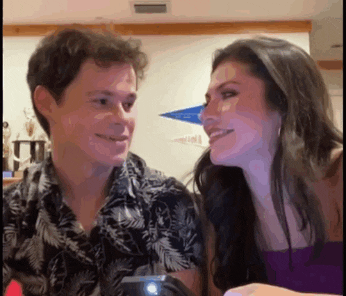 a man and a woman are looking at each other and smiling while sitting next to each other .