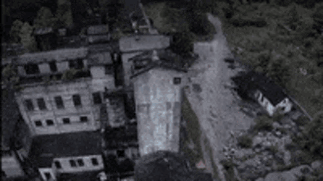 an aerial view of a destroyed building with a lot of trees in the background