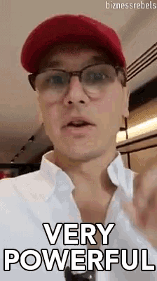 a man wearing glasses and a red hat is giving a very powerful speech .