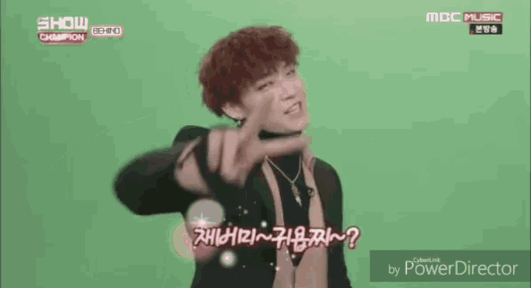 a man with red hair is making a peace sign while wearing a black jacket and turtleneck .