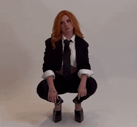 a woman in a suit and tie is sitting down