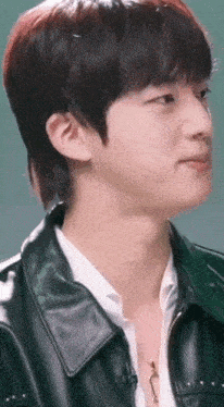 a close up of a person wearing a leather jacket and a necklace .